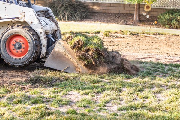 Small Bulldozer Removing Grass From Yard Preparing For Pool Installation.